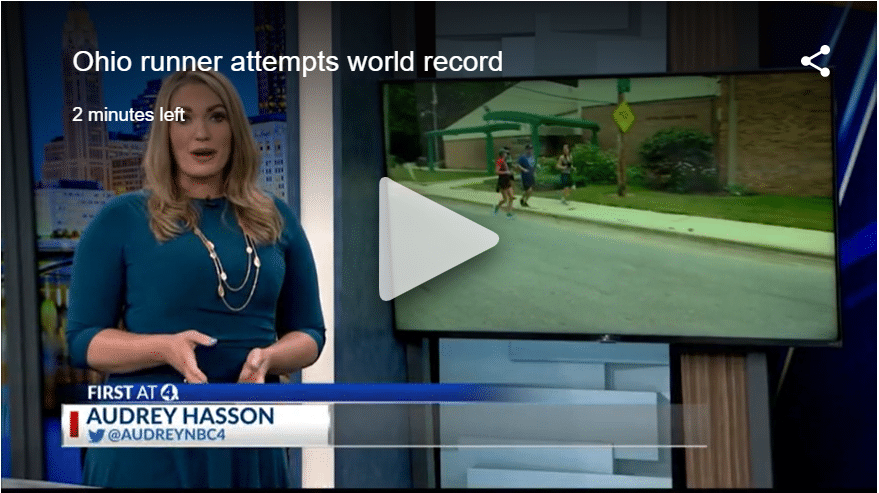 Screenshot of news anchor live with running footage on screen behind