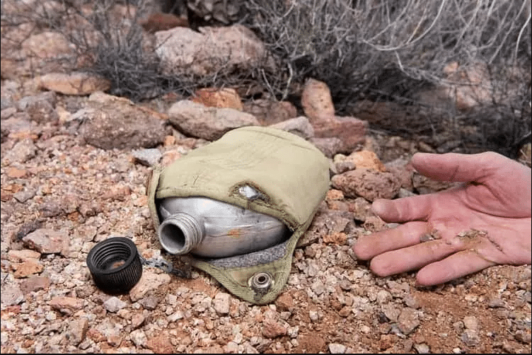 A hand next to an empty water canister on the ground