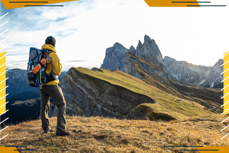 Hiker on grassy tundra staring at mountains