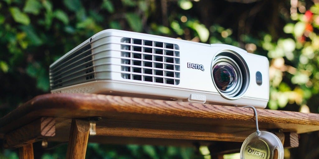 A movie projector sitting on a wooden table outside