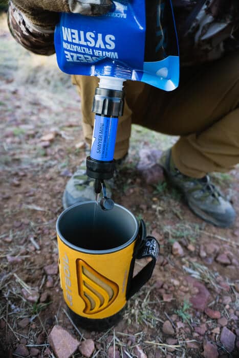 Person filtering water from Sawyer squeeze into Jetboil stove Photo credit: Josh Kirchner