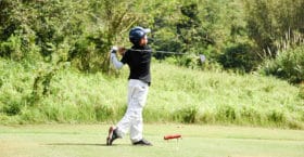 Child swinging golf club on course