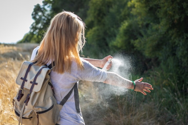 Hiker spraying bug spray on self