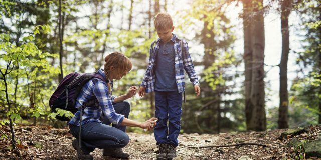 Mother sprays tick repellent on sons shoes