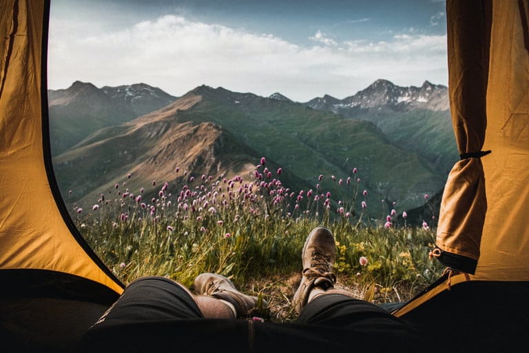 Hikers feet with boots on looking out through tent door toward mountains