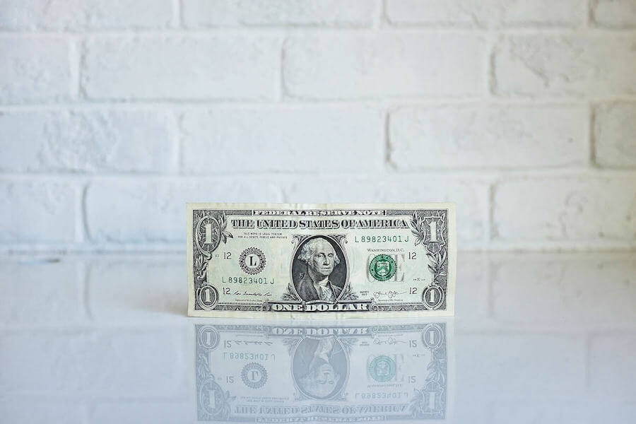 dollar bill standing on white reflective table travel nurse pay