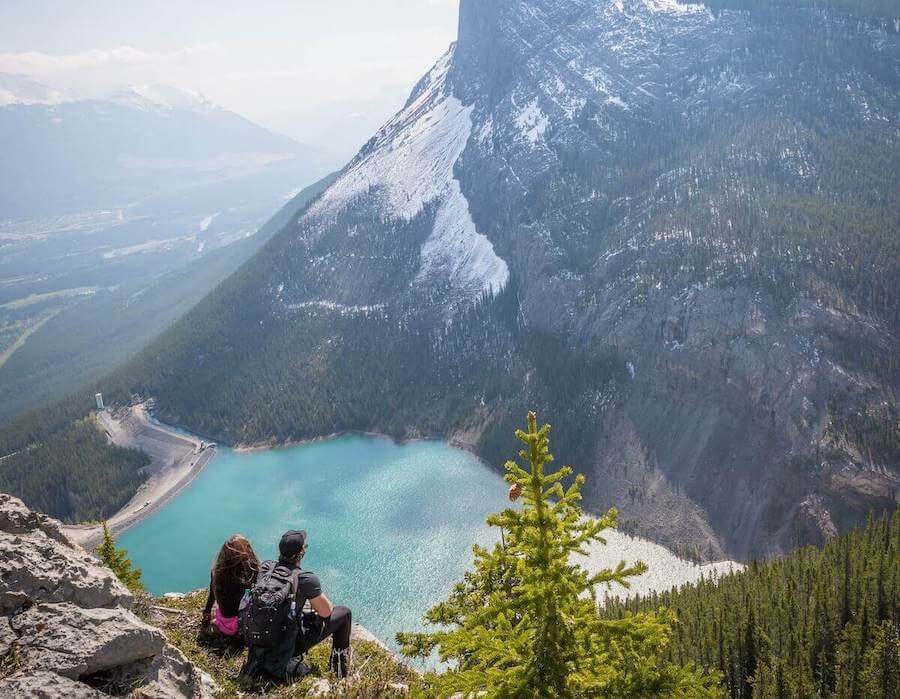 two people sitting on edge of cliff of mountain landscape travel nurses