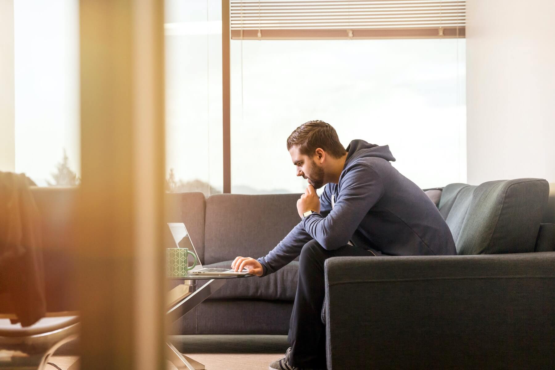 man on sofa looking at laptop on coffee table nurses make yourselves discoverable