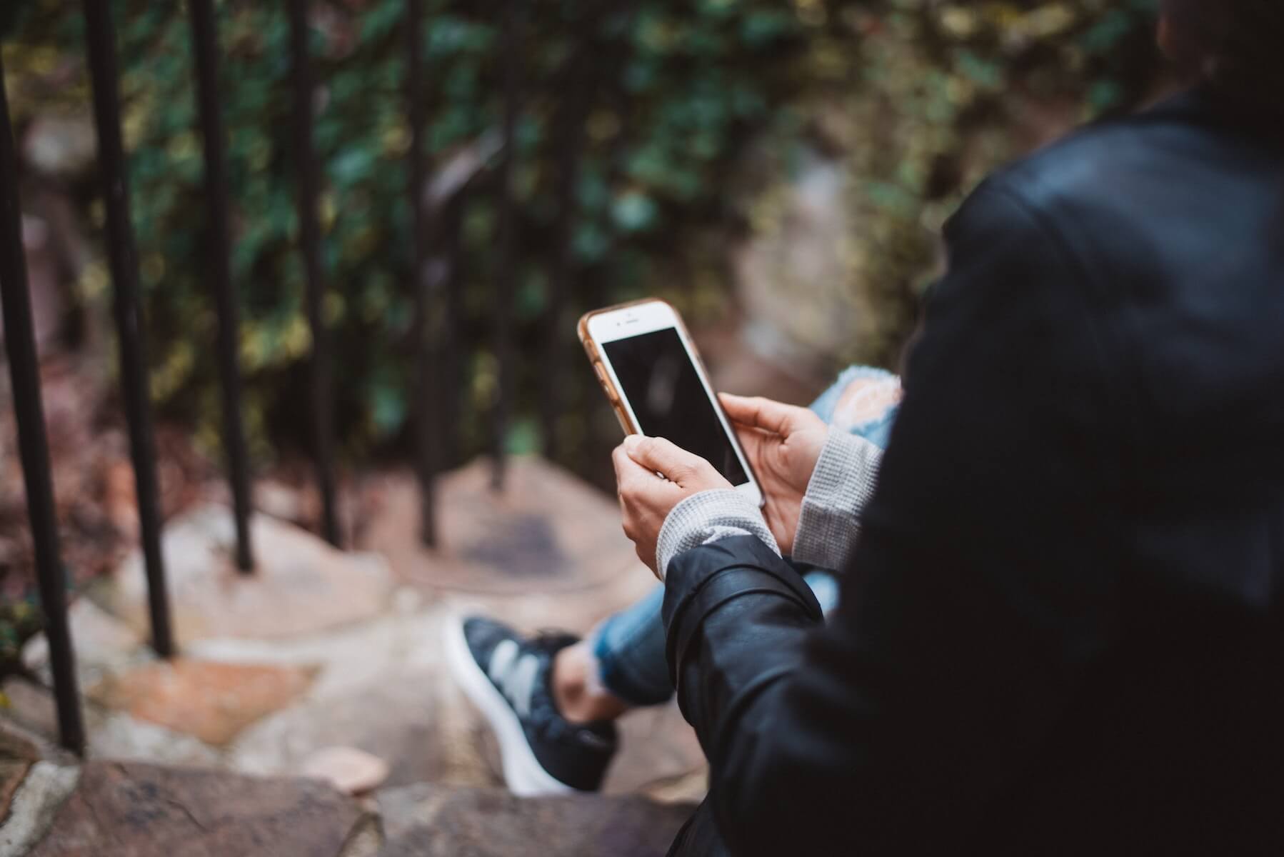 woman sitting outside on steps looking at phone remote nursing jobs covid19 telehealth