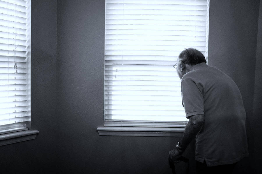 elderly man looking out of window in nursing home