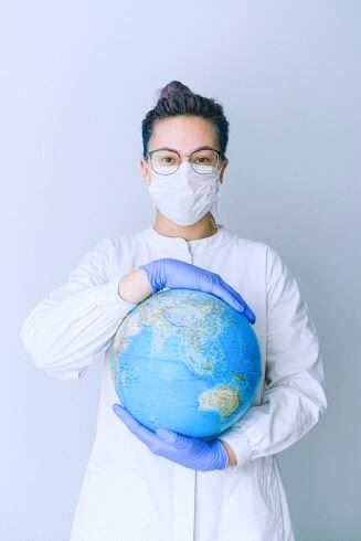woman holding globe with mask and gloves on travel nursing jobs