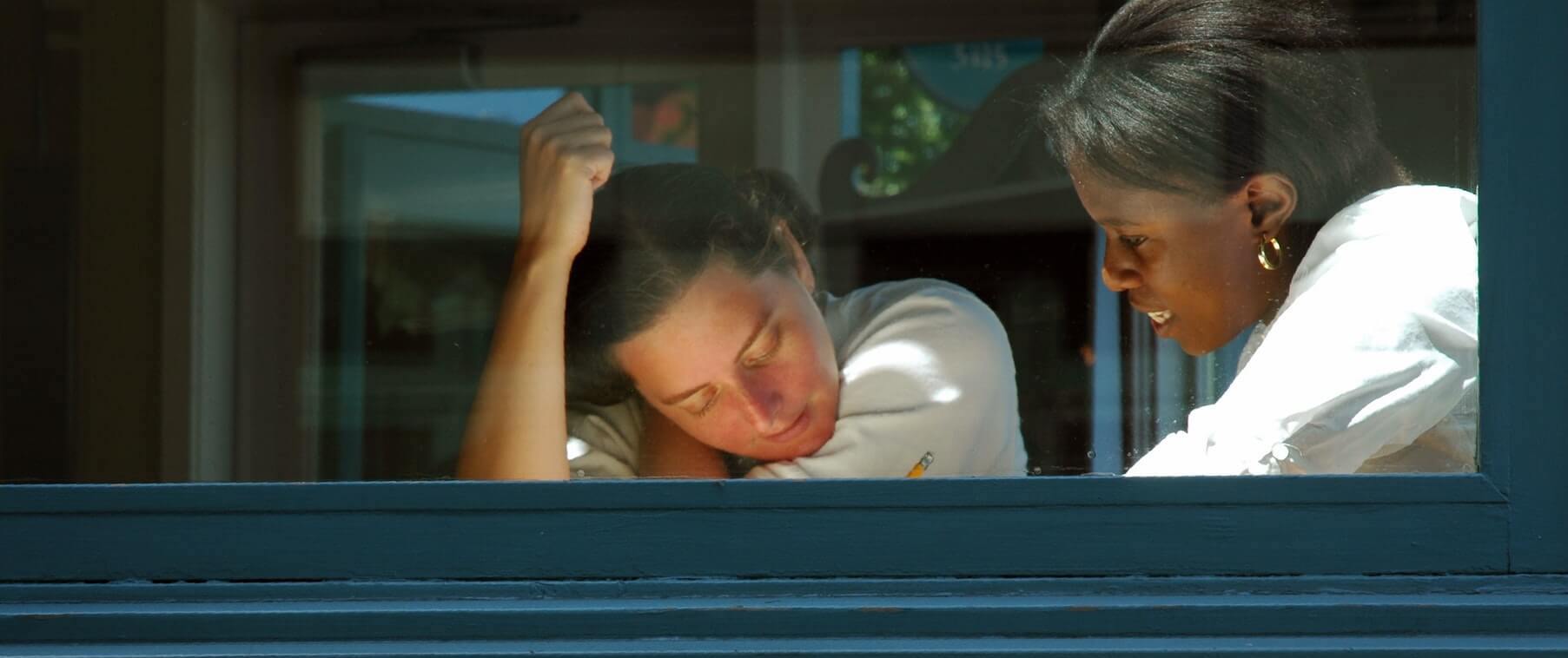 two women sitting at table looking at paper with pencil in hand studying for nursing school