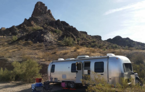 RV parked in desert in front of small mount nomadic nurse