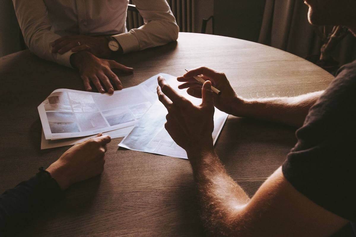 three people with hands on table discussing paperwork on table travel nursing agencies travel nursing contracts