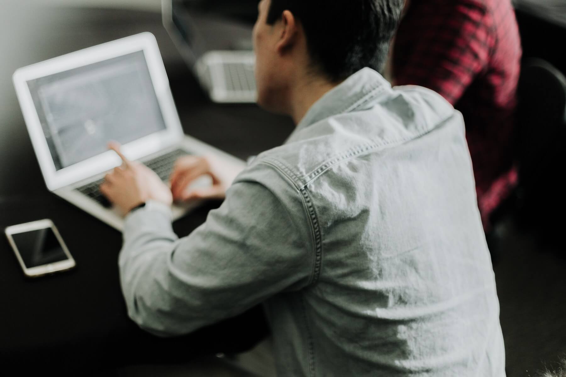 man sitting down looking at laptop working during nursing school