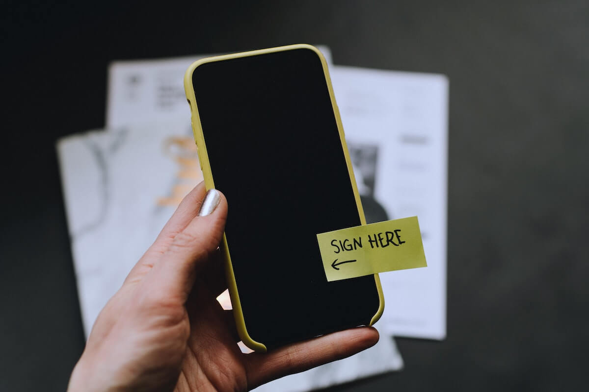 iphone hovering in front of paperwork with sticker saying sign here how to become a travel nurse