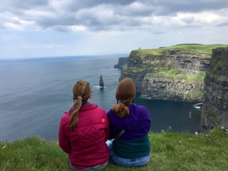 travel nurse duo watching over ocean on grassy cliffs