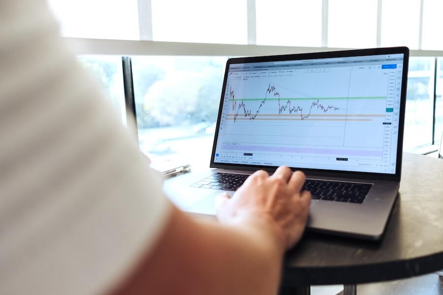 man typing on computer with graph of money over time nurse finances