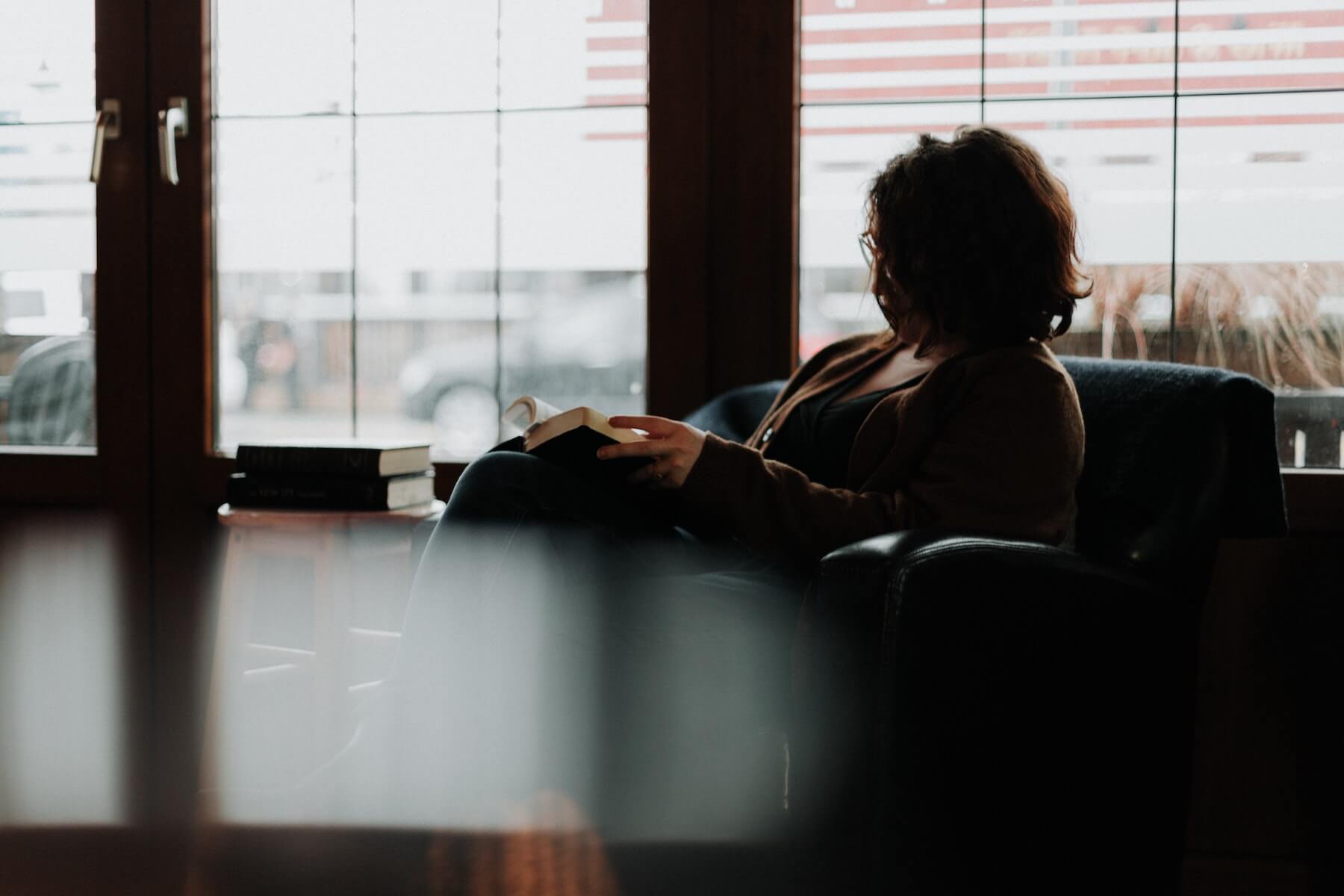 woman sitting in chair reading relaxing nurse stress unwind after work