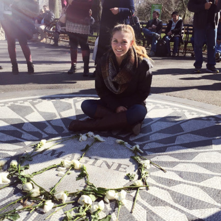 photo of brit hamstra sitting on ground by flowers smiling pediatric nurse