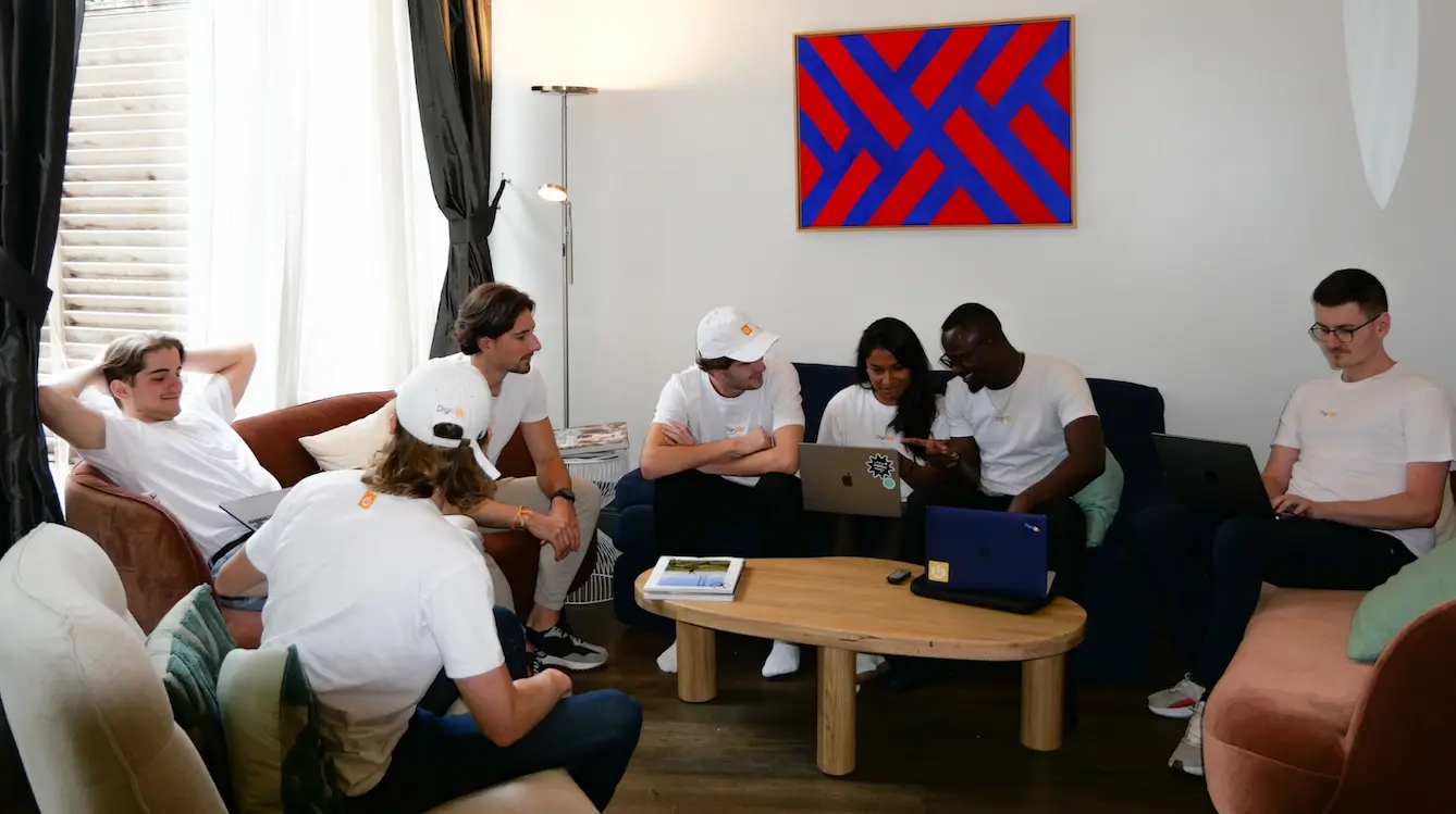 L'ensemble de l'équipe Digidop travaillant avec des ordinateurs assis sur des canapés autour d'une table