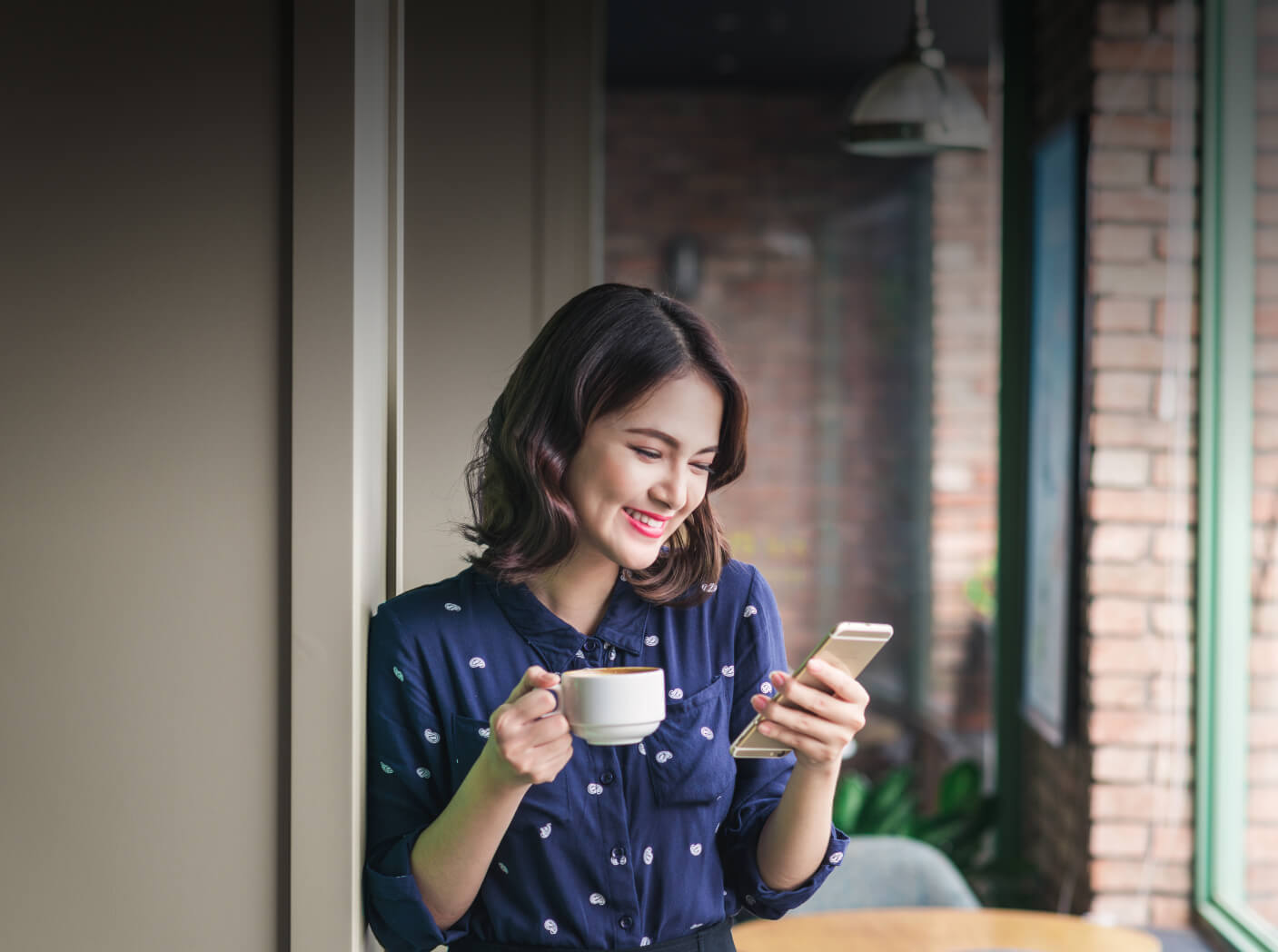 Person holding cup of coffee and their phone, using the Monorail wishlist app.