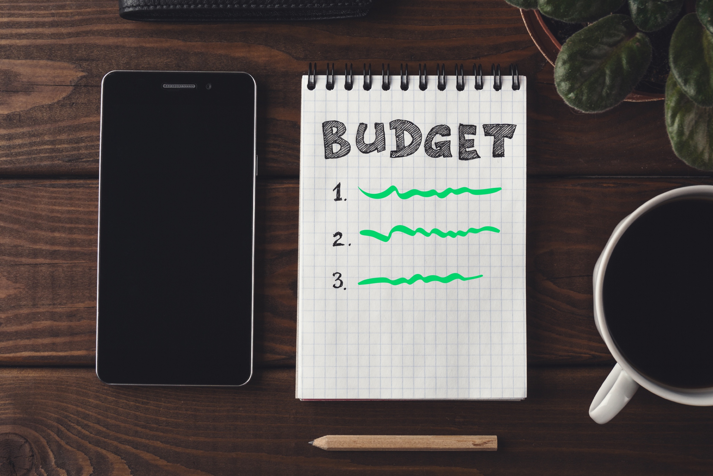 A phone and bulleted list on a notepad showing a budget percentage breakdown.