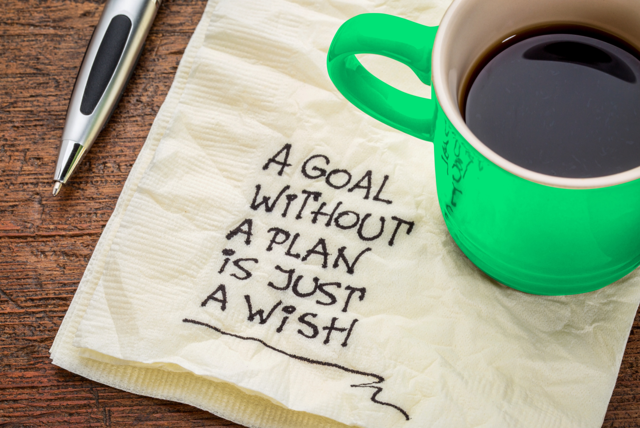 A note written on a napkin reads a money goal without a plan is just a wish.