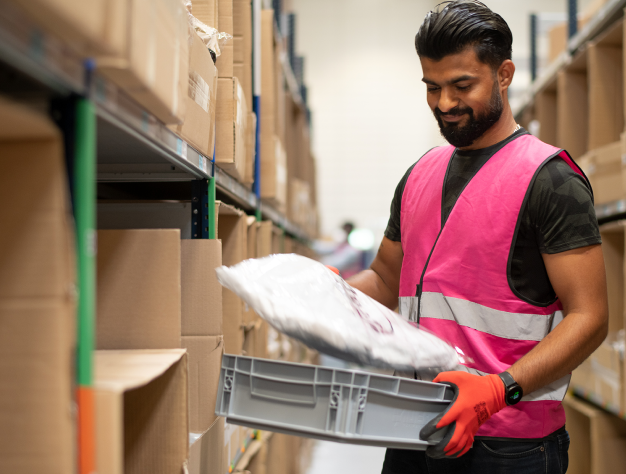 Fulfillment center employee picking an order and placing it into picking basket