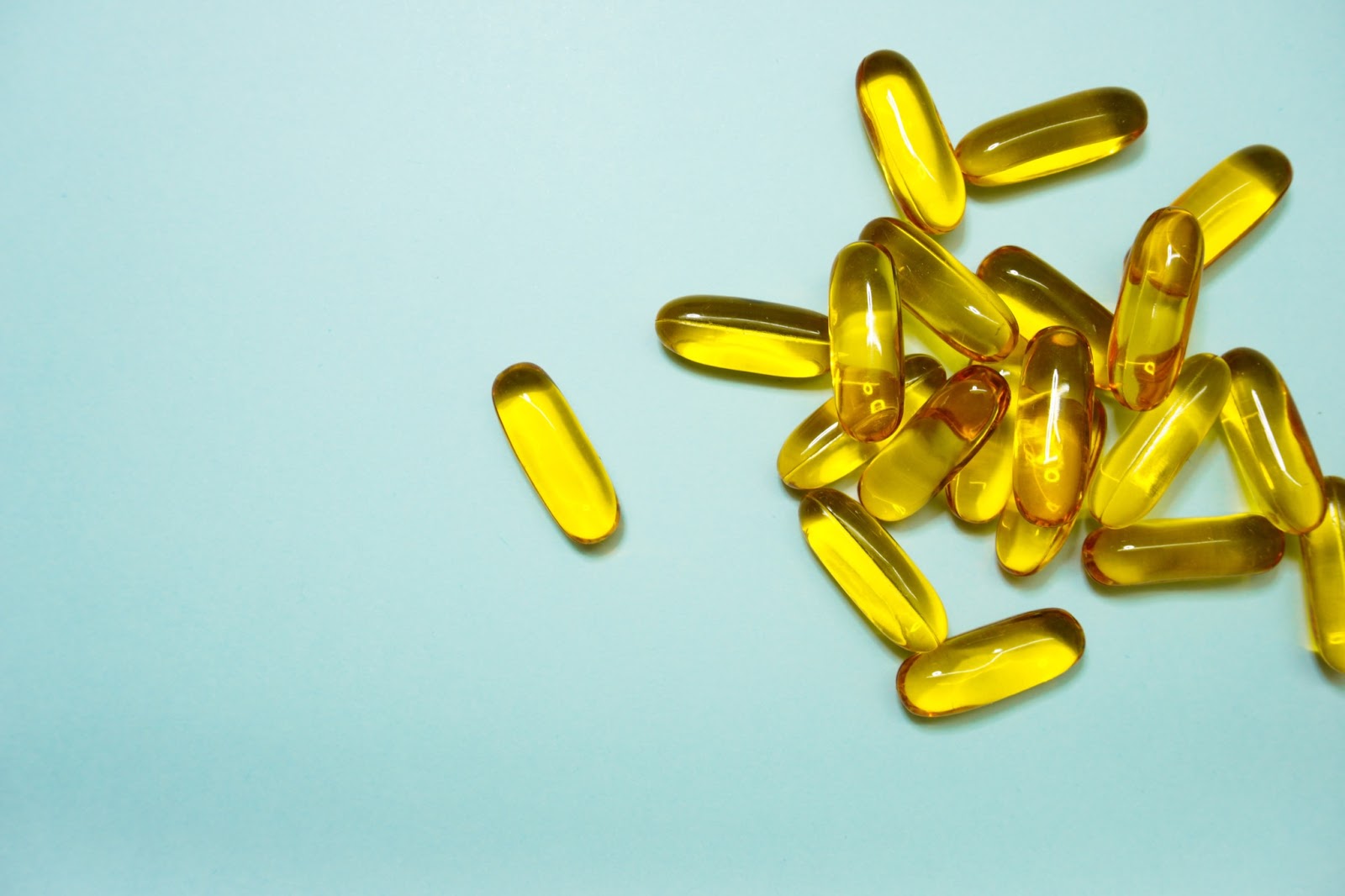 image of yellow supplement pills on a blue background