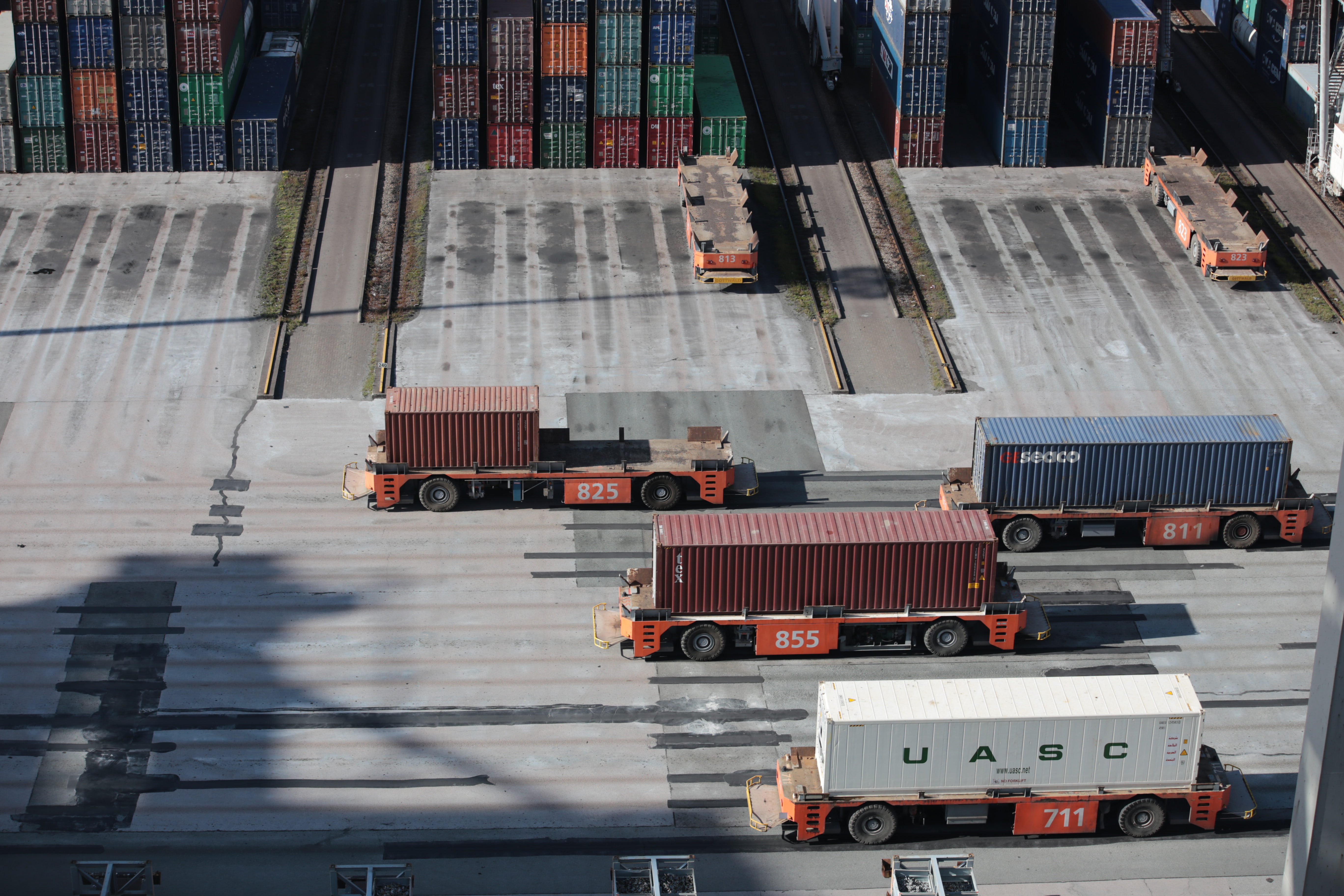 image of truckloads of freight shipping containers being loaded in the dockard