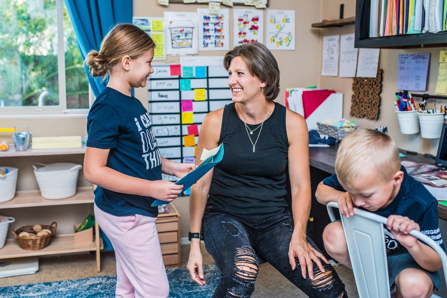 A Prenda Guide smiling assuringly at a microschool student holding homework.