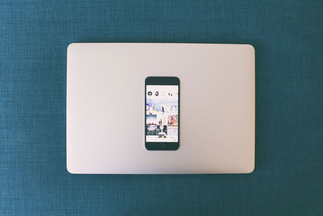 Image contains a phone over a laptop on the table