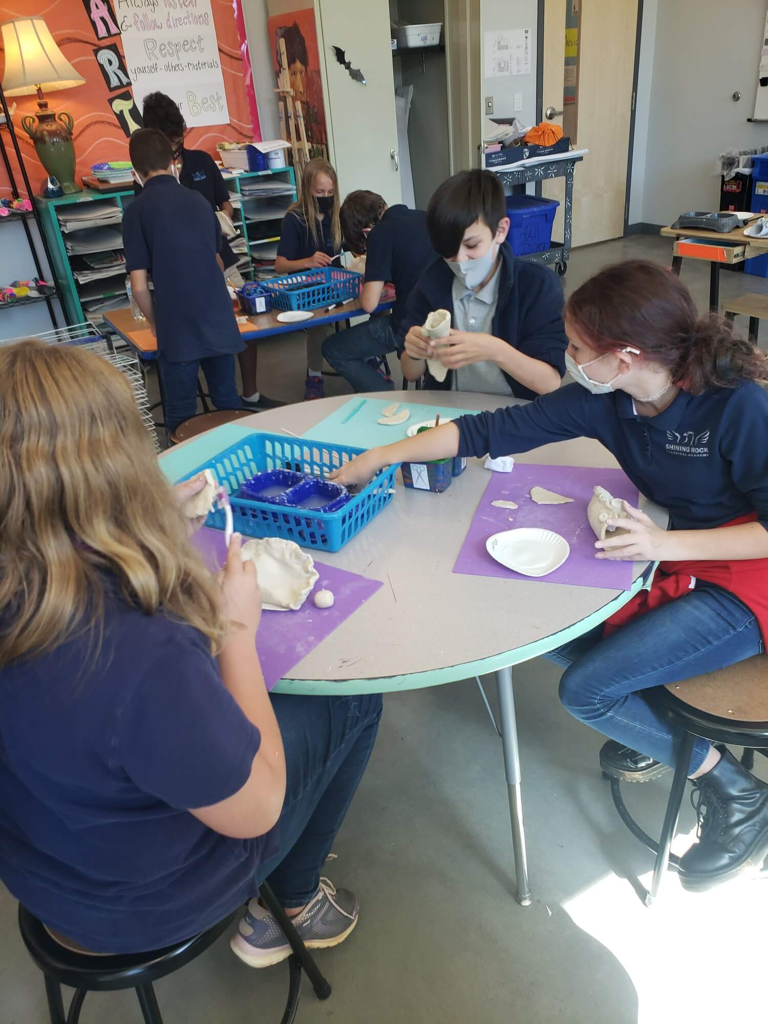 Students in the lower school at a table working on crafts