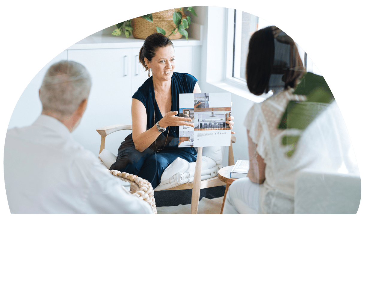 A female presenting a brochure showing a picture of a kitchen to another couple