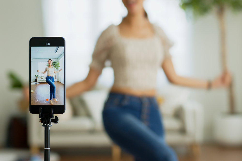 Tripod holding a phone and recording a woman dancing.