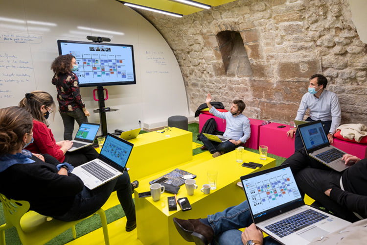 A group of people are gathered in front of a MeetingBoard for a workshop