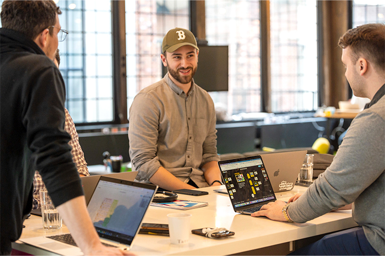 Three people in front of their laptop exchange ideas