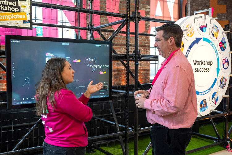 Two experts discuss a topic in front of a Board