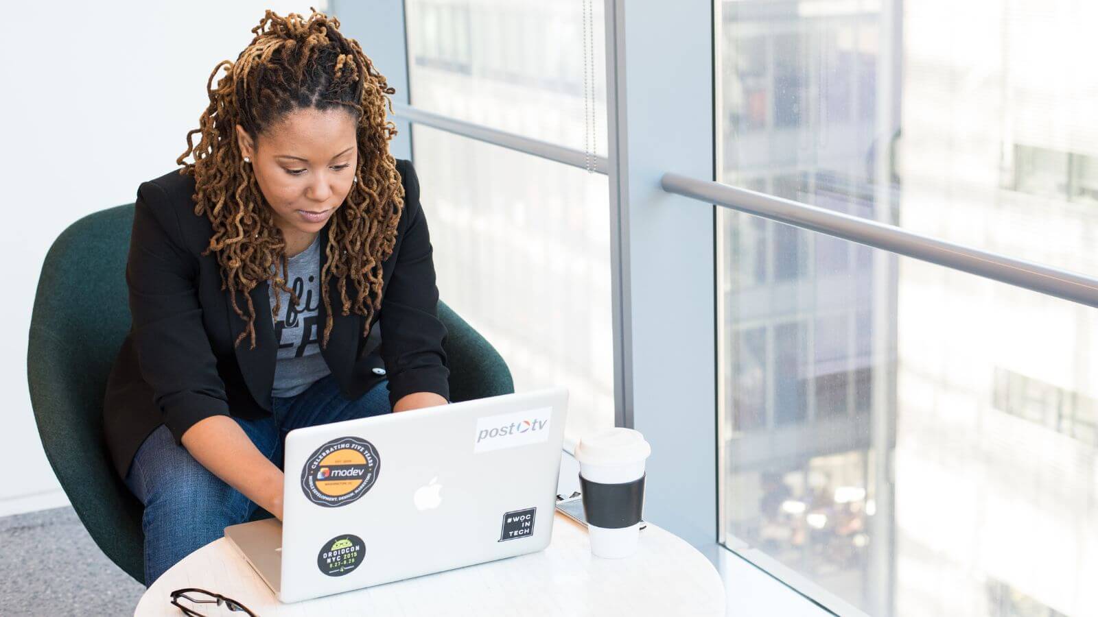 Woman working on laptop drinking coffee