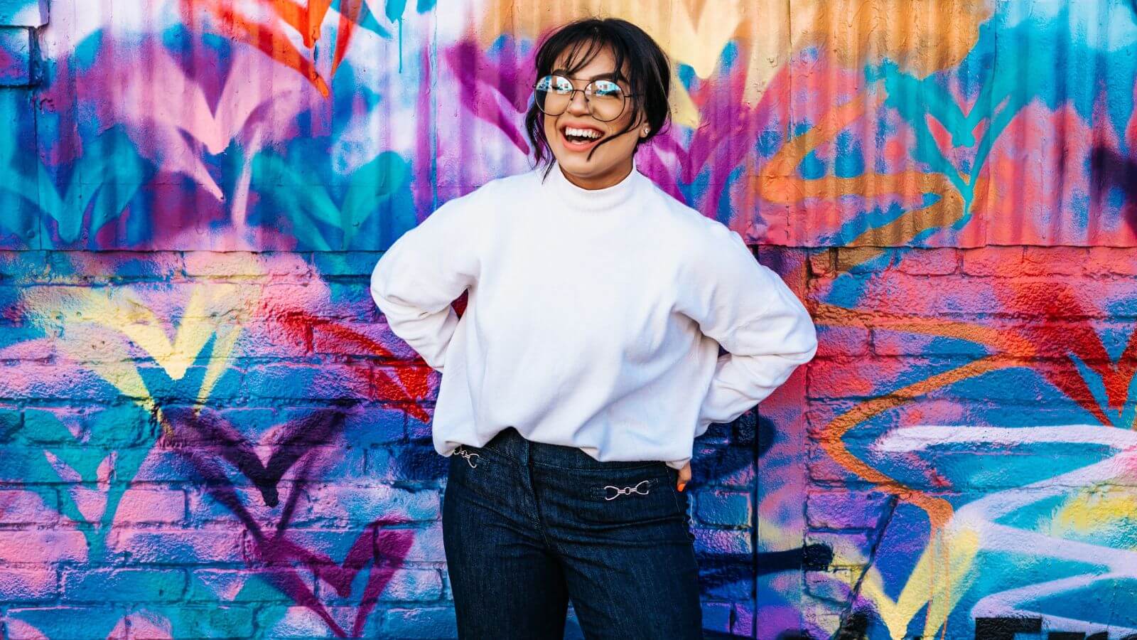 Woman standing in front of a wall covered in colorful graffiti