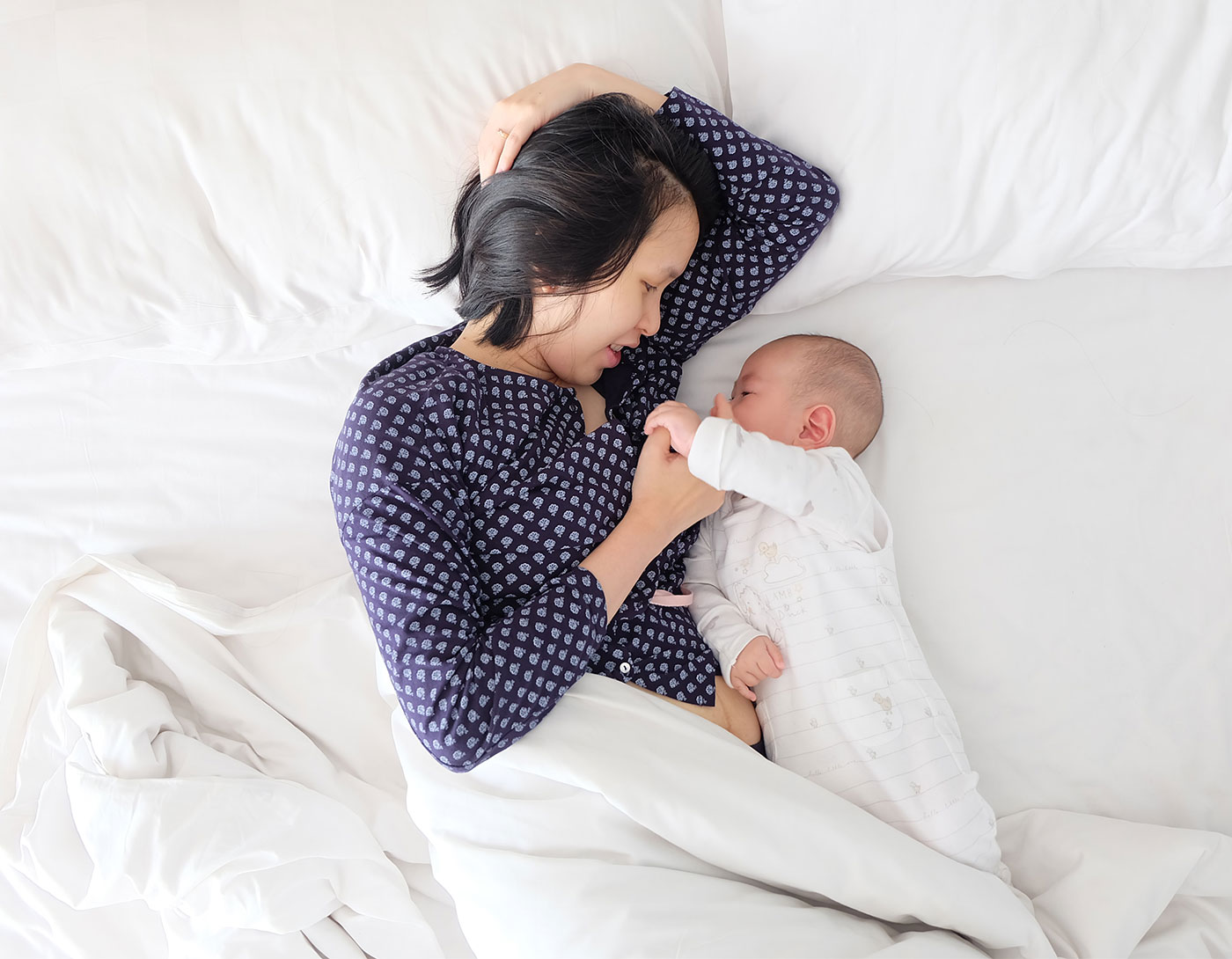 young mother laying in bed cuddling her baby