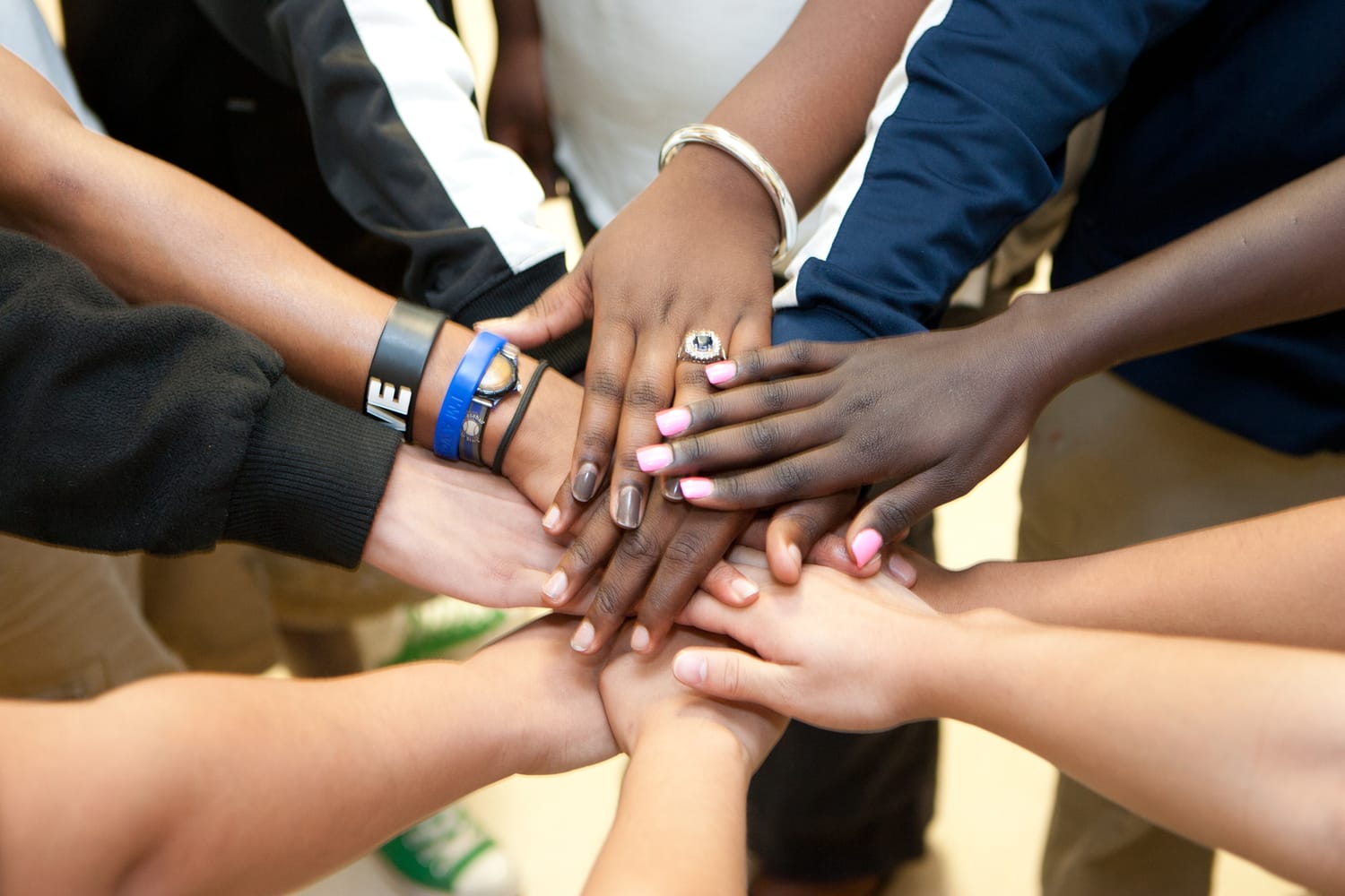 People in a circle putting their hands together in the center