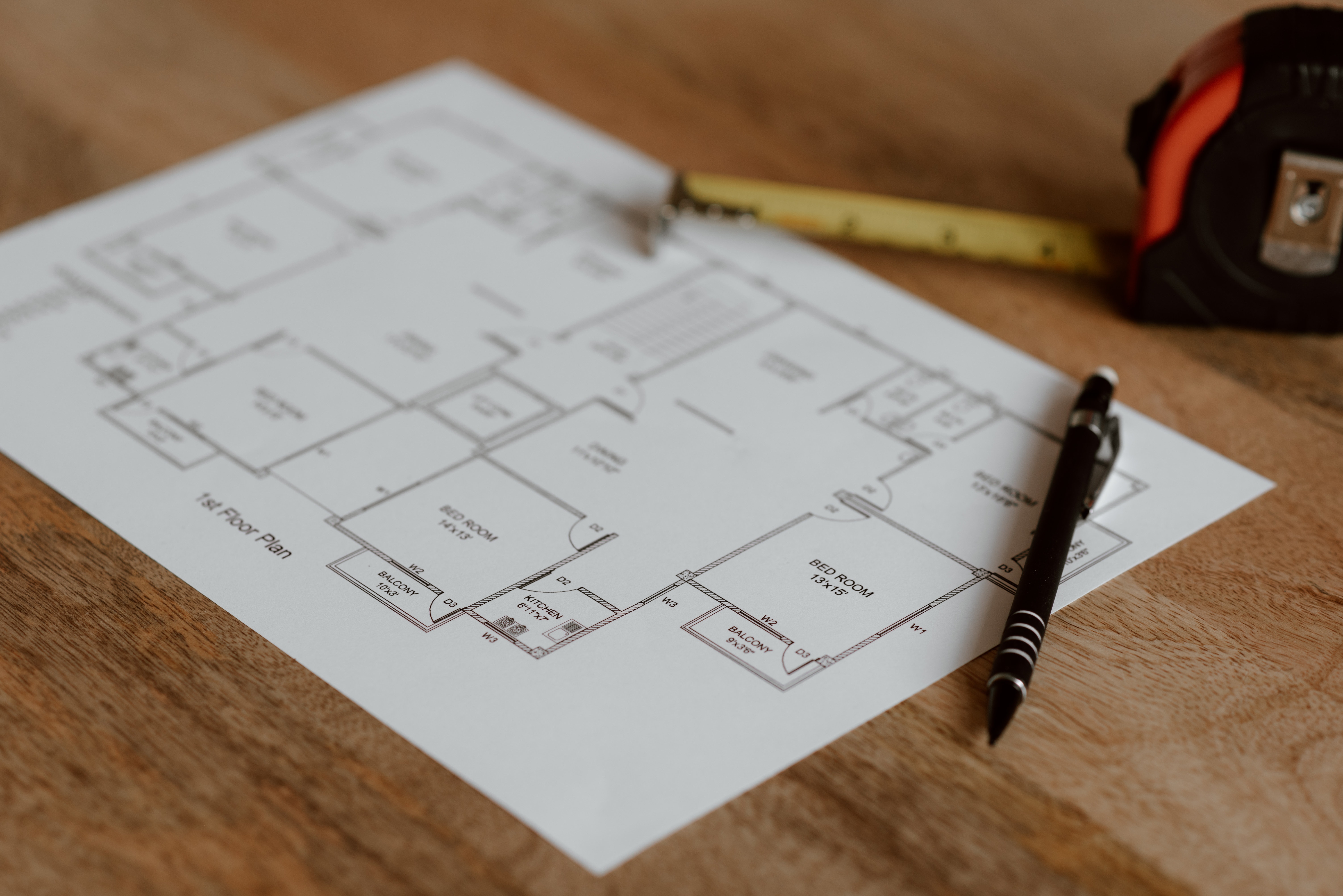 Construction documents on a desk with a tape measure and a pen