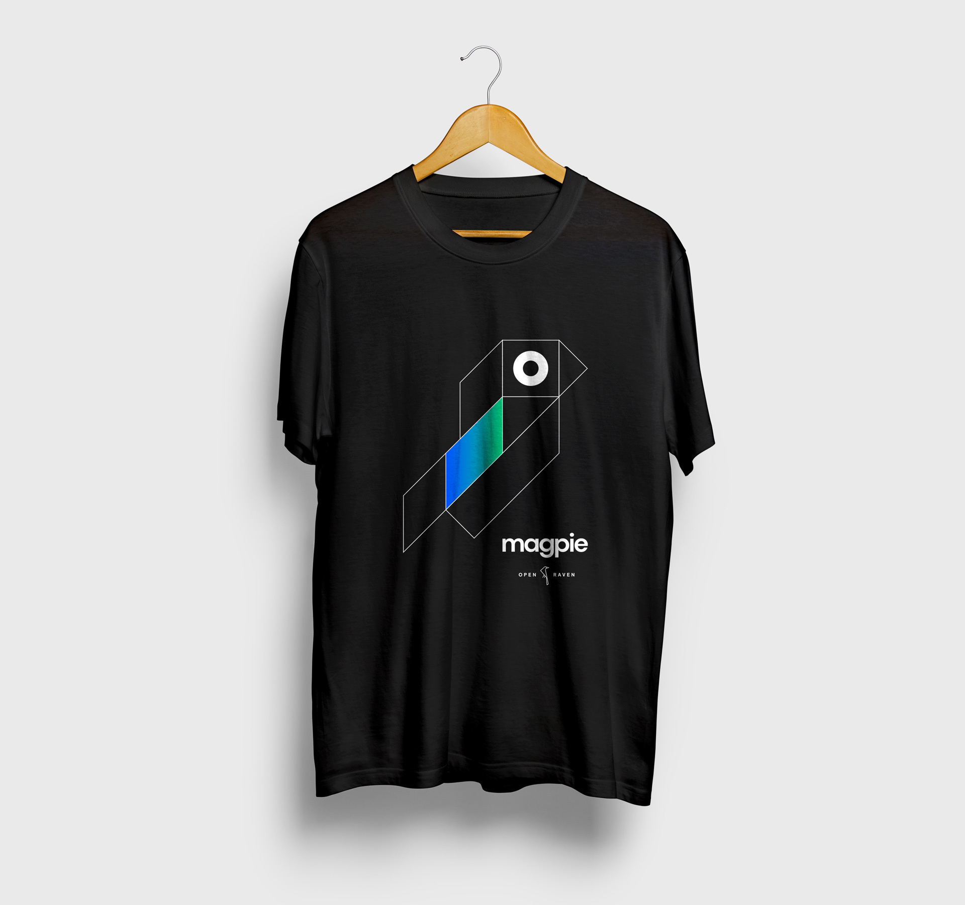 Black T-shirt on a hanger with a print of the Open Raven Magpie logo