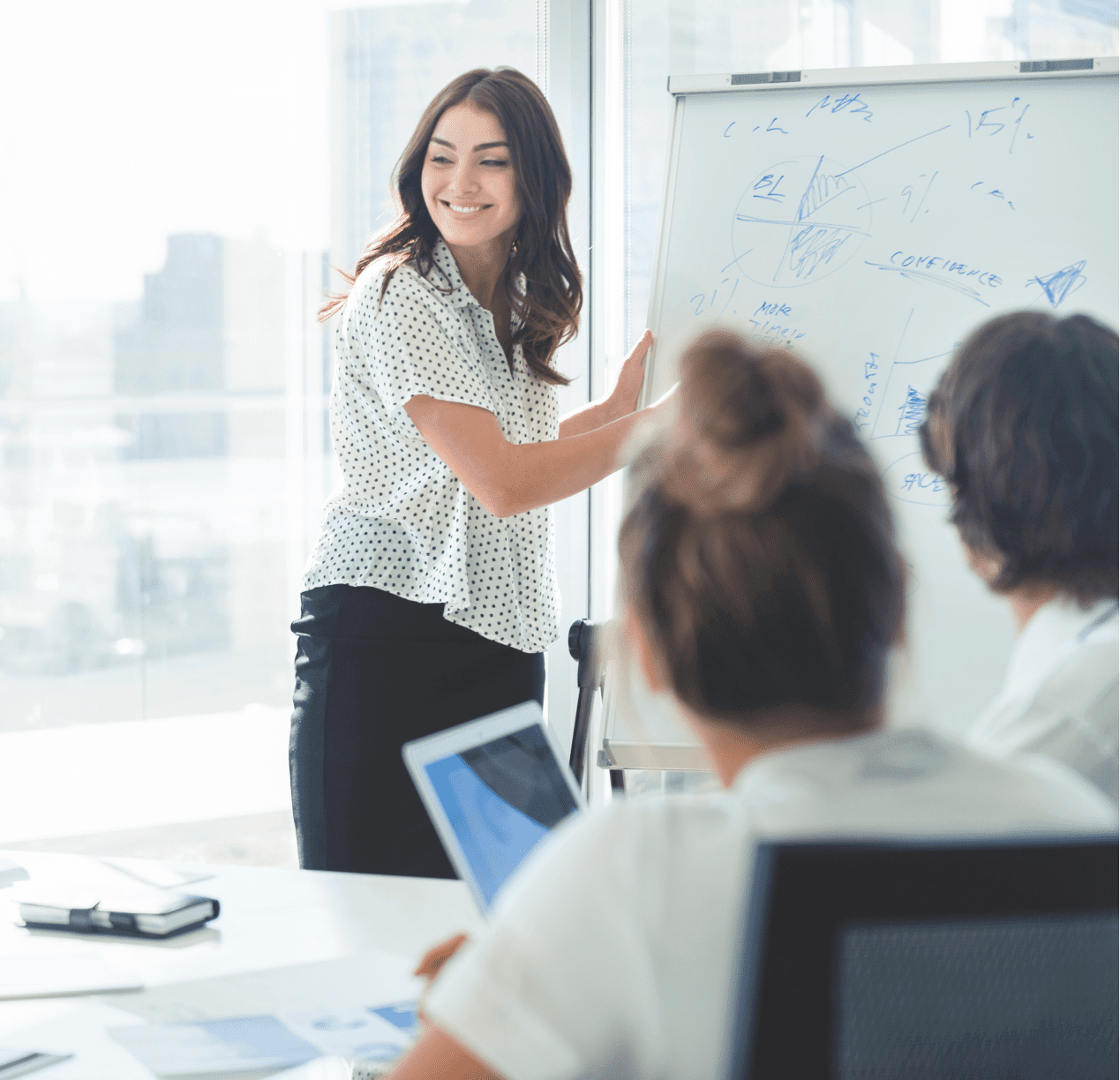 会議室のホワイトボードの前でミーティングの進行役を務める女性社員の画像