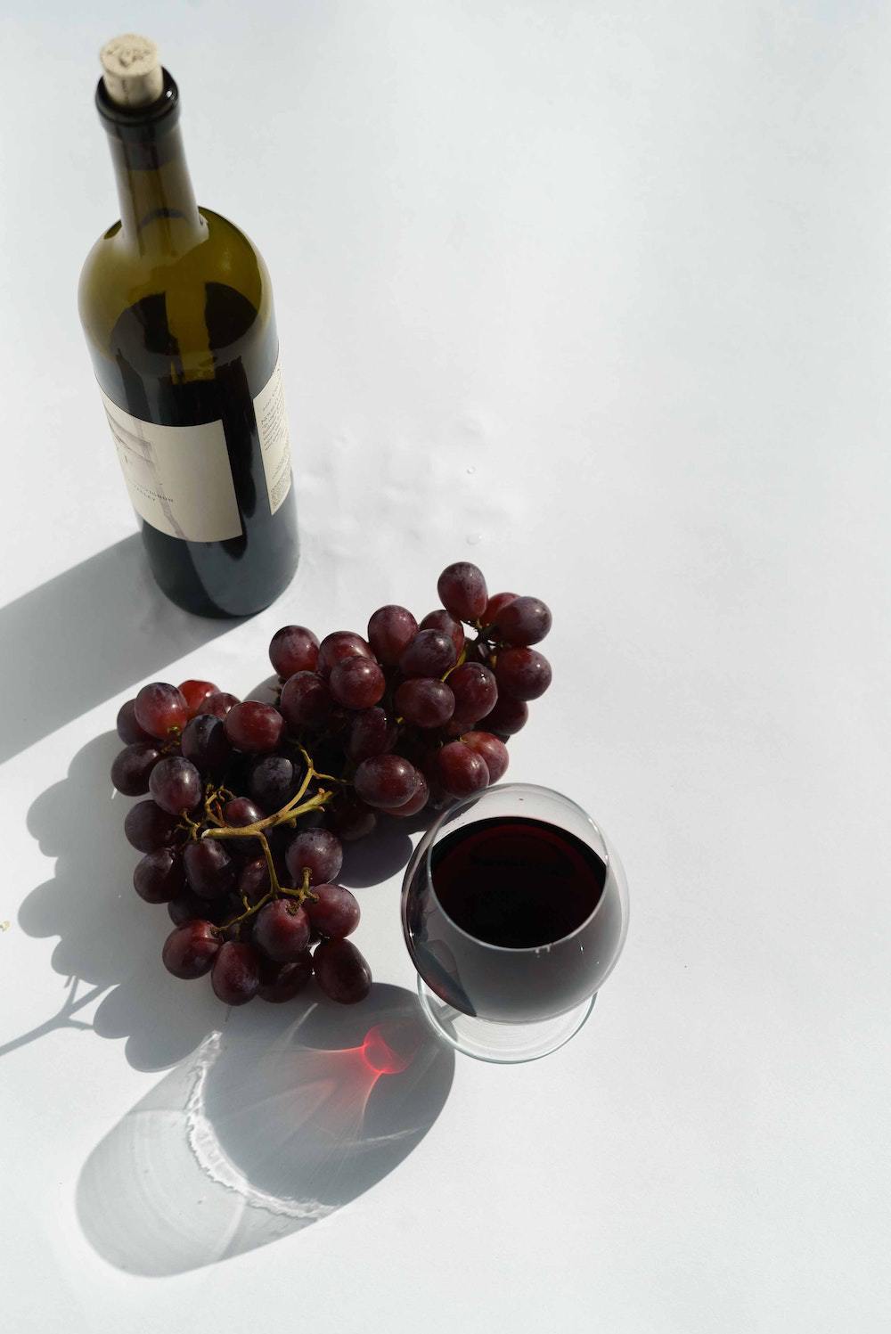 A bottle of wine, a glass of wine and grapes