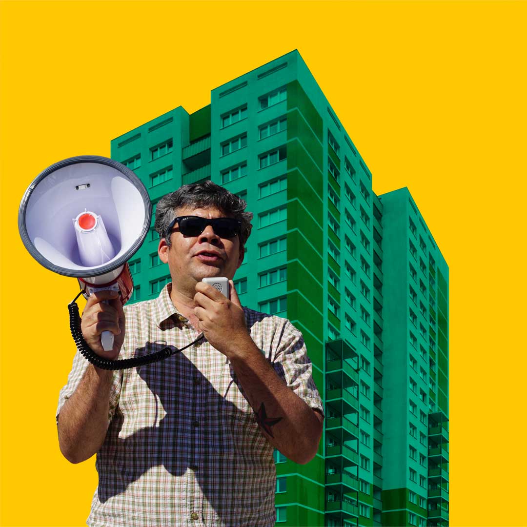person speaks into bullhorn in front of yellow sky and green building