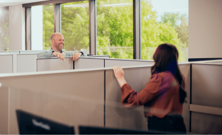 Two Christensen Group Insurance employees speaking and laughing in the office