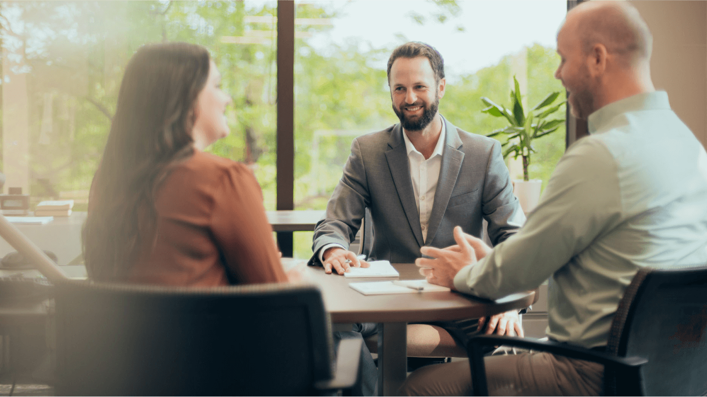 Smiling Christensen Group Insurance agent meeting with two clients in an office